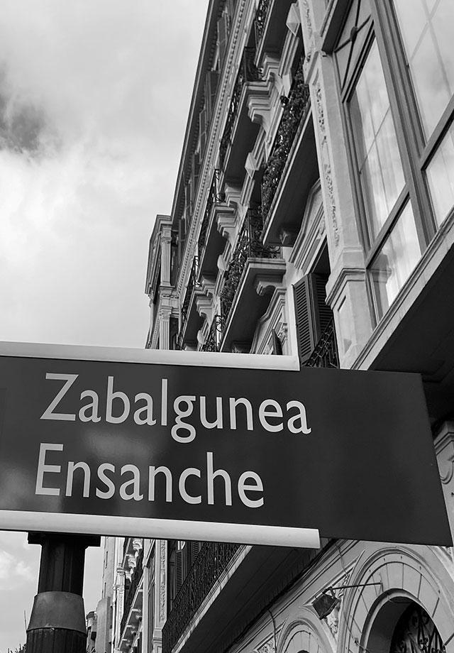 Cartel de señalización de la ubicación en Plaza del Ensanche de la oficina de m2 inmobiliaria en Bilbao.